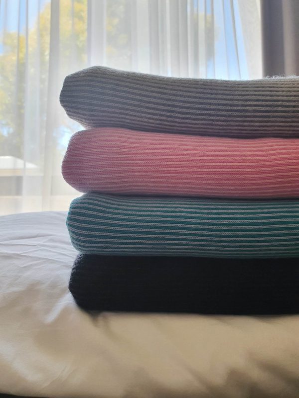 Stack of folded Bobbi Merino Wool Baby Blankets in silver, aqua, charcoal, and Taffy. Perfect for every new parent and nursery decor.
