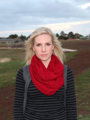 A lady standing outdoors wearing a Red Branberry Wool Infinity Scarf
