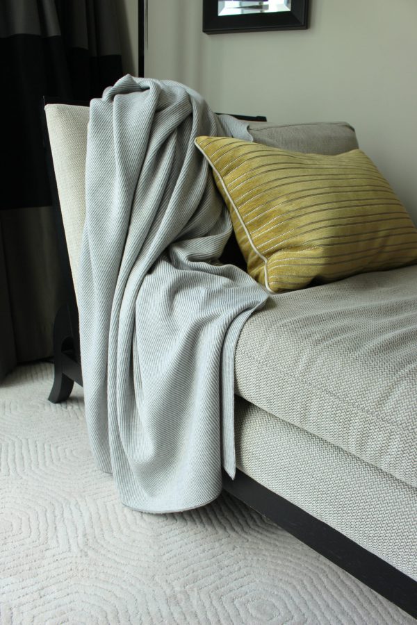 Silver Merino Wool Blanket in contrasting colours of grey and white, draped over a luxurious chaise lounge.