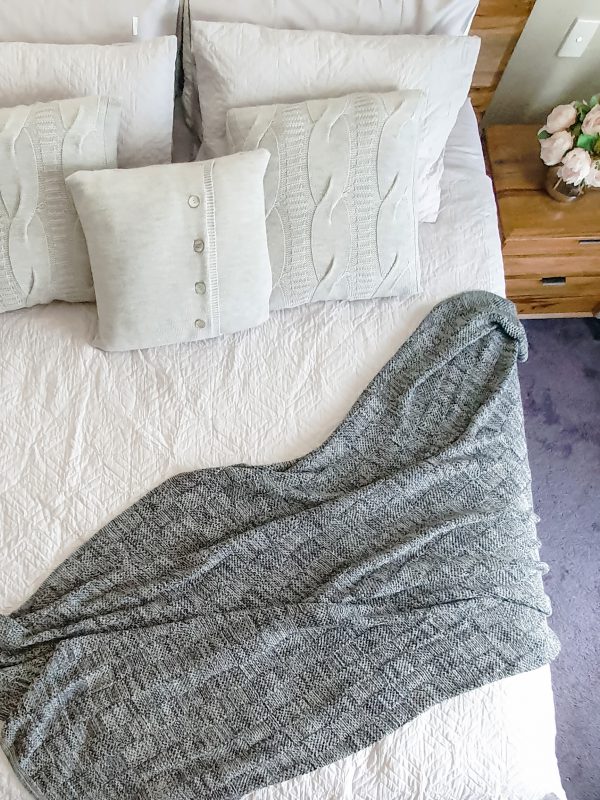 Pure Merino Wool Marley Blanket in Basalt (dark marl), top view on bed with light grey cushions and doona. Strewn diagonally for a stylish bedroom arrangement.