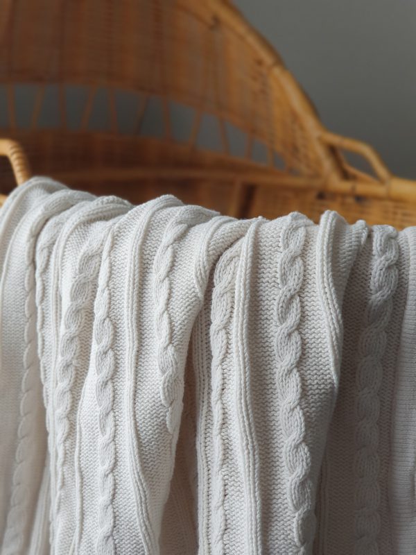 Cable Knit Blanket in Milk (Light Cream) - Close up view showcasing the intricate cable knit pattern. Irresistibly warm and timeless, perfect for nurseries or as a stylish accent.