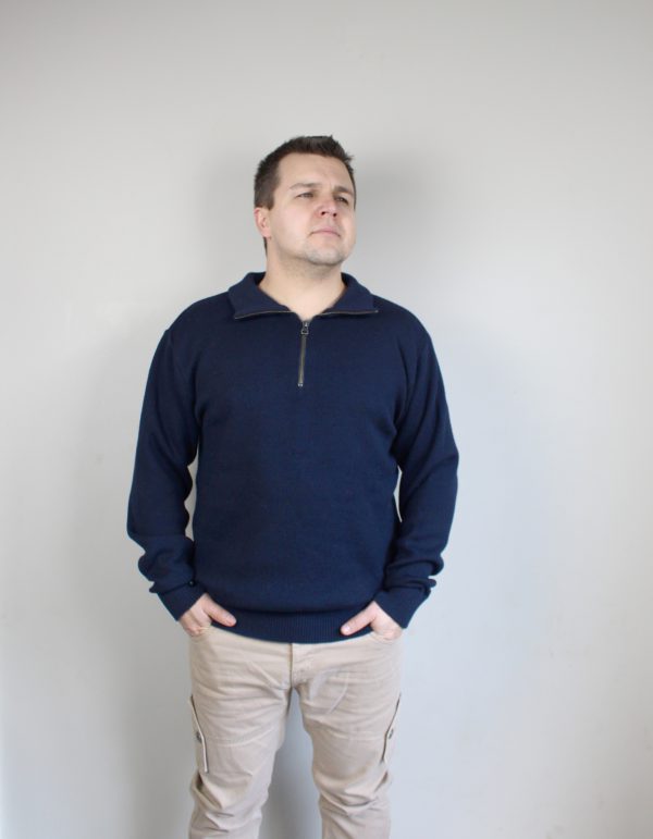 A man standing indoors wearing an Australian Made, pure merino woollen Branberry knitted jumper with zip neck in Marine (navy marl).