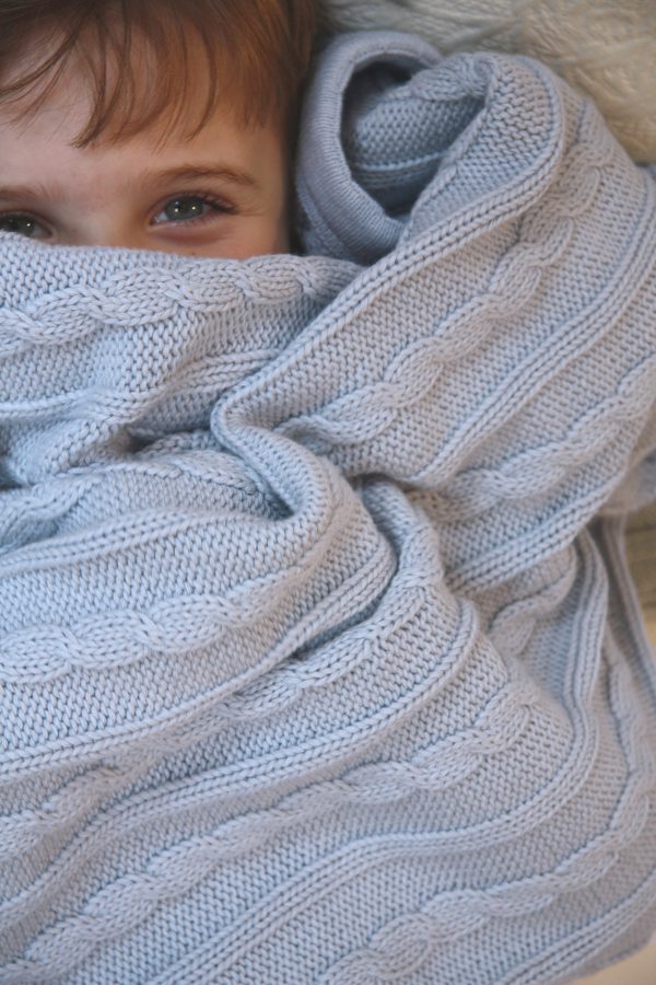 A baby wrapped up in an Branberry Australian Made, Cotton and Merino wool blend Cable Blanket in Pale Blue