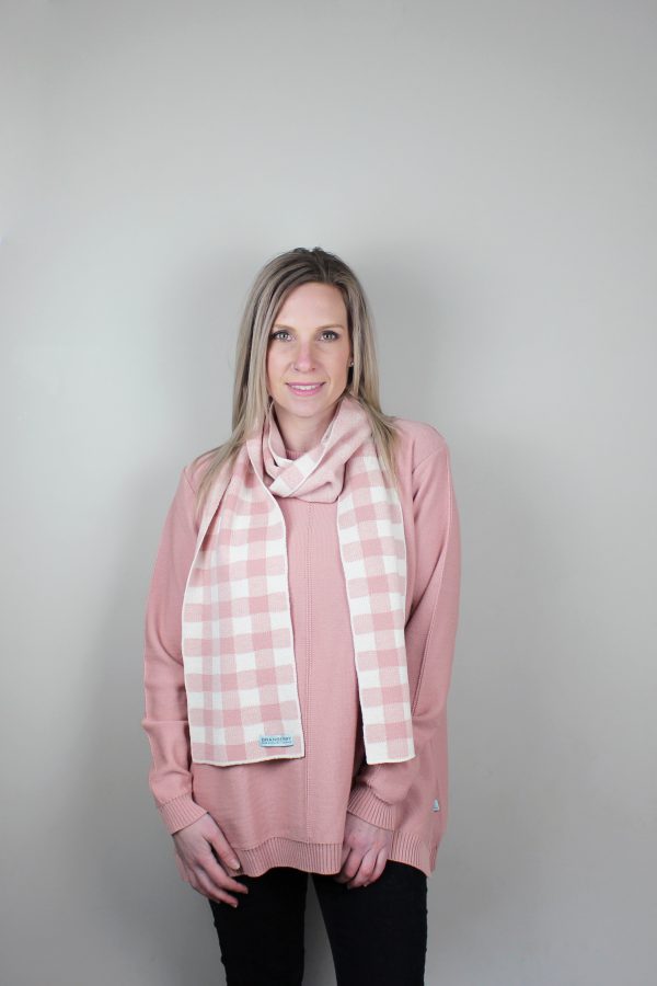 A Lady standing indoors wearing a Branberry Australian Made wool Gingham knitted scarf in French Rose and white. (pale pink)