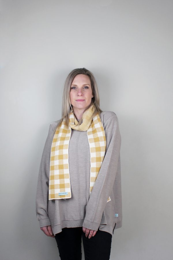 A Lady standing indoors wearing a Branberry Australian Made wool Gingham knitted scarf in Mustard and white.