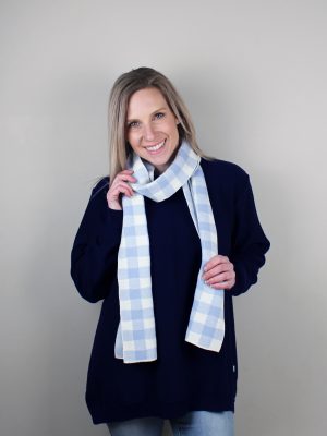 A Lady standing indoors wearing a Branberry Australian Made wool Gingham knitted scarf in Powder Blue and white. (Pale blue)
