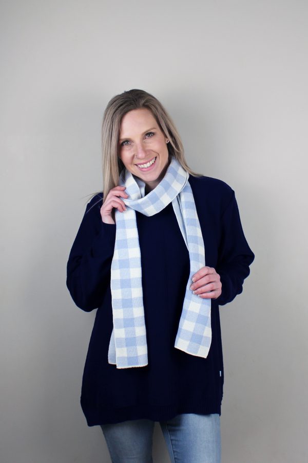 A Lady standing indoors wearing a Branberry Australian Made wool Gingham knitted scarf in Powder Blue and white. (Pale blue)