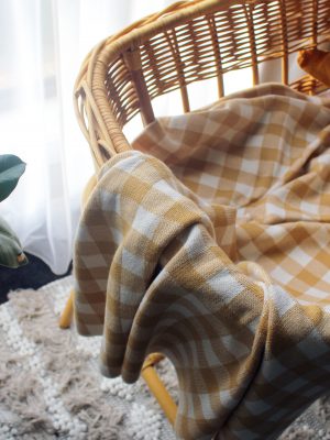 Australian Made Branberry, Pure Merino Wool Gingham Throw Blanket in Muistard and White, hanging on a bassinet.