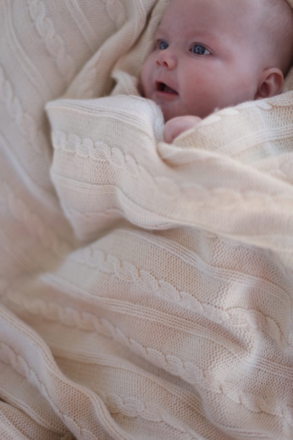 A baby wrapped up in an Branberry Australian Made, Cotton and Merino wool blend Cable Blanket in Milk White