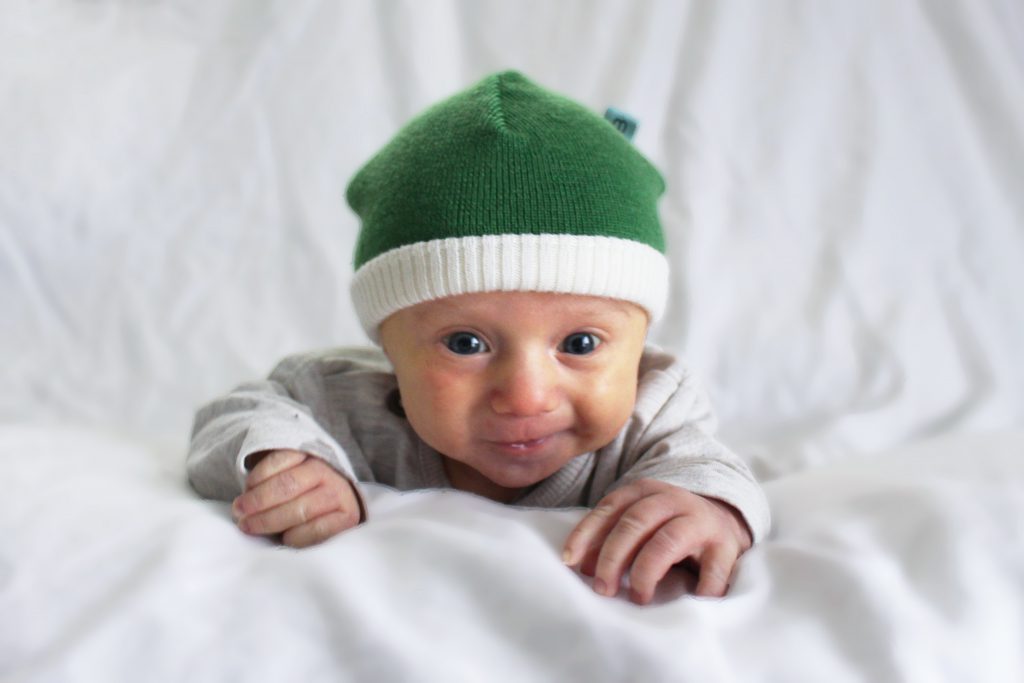 a cute baby wearing an Australian Made, Branberry Apple Green Zest Beanie.