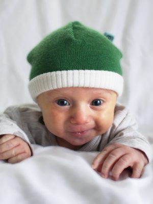 a cute baby wearing an Australian Made, Branberry Apple Green Zest Beanie.