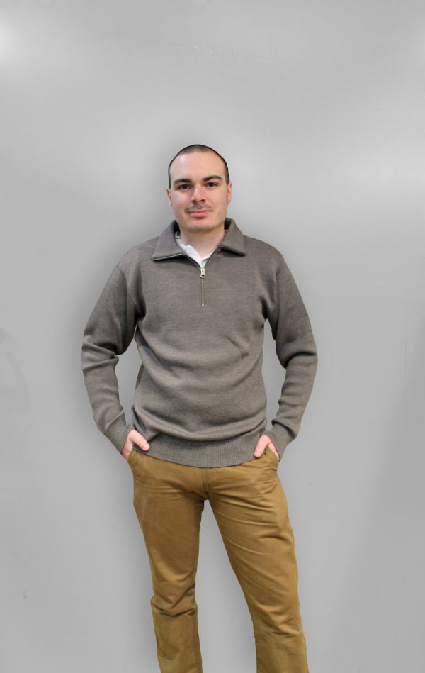 A man standing indoors wearing an Australian Made, pure merino woollen Branberry knitted jumper with zip neck in Mocha Brown.