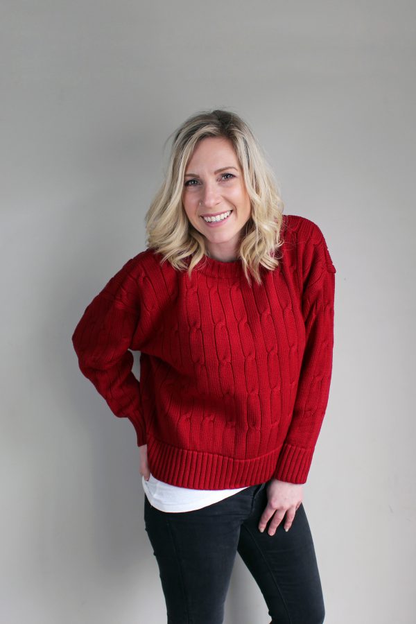 A lady wearing an Australian Made, Branberry merino wool cable crop, crew neck jumper in Sangria Red