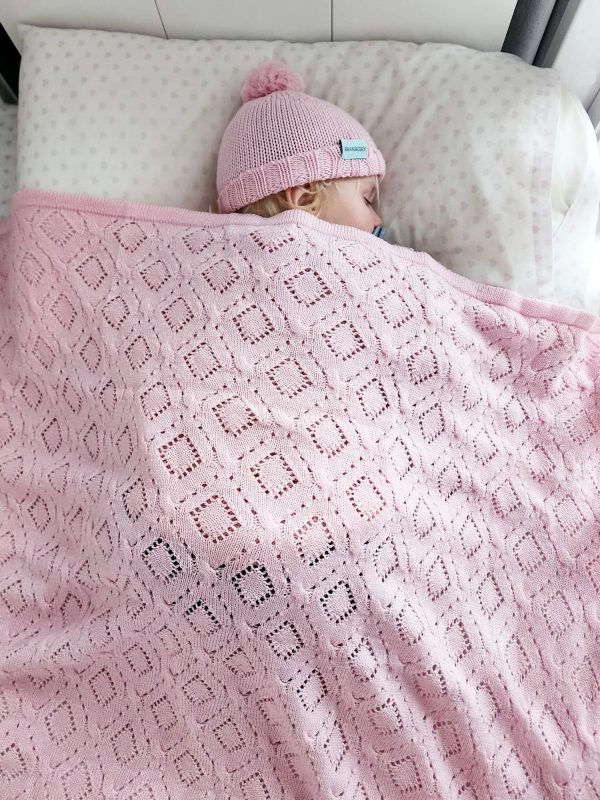 Branberry Heirloom Blanket in Pink Silk, a second adorable image of a baby sleeping peacefully in a cot with the matching Pure Wool Frankie Beanie.