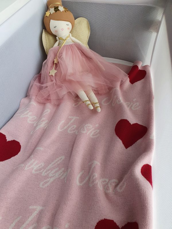 A bassinet set up with a fairy doll and a pure merino wool, personalised love hearts blanket in a pink, raspberry and white colour combo.