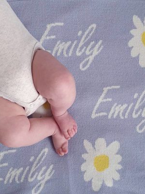 A baby laying on a Personalised Name Blanket with Daisy flowers in a Pastel Blue colour. Made from Pure Australian Merino Wool and Made in Australia.