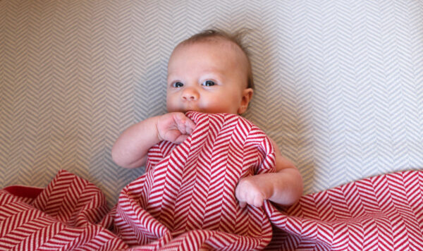 Baby Hiding under Red and White Herringbone Blanket