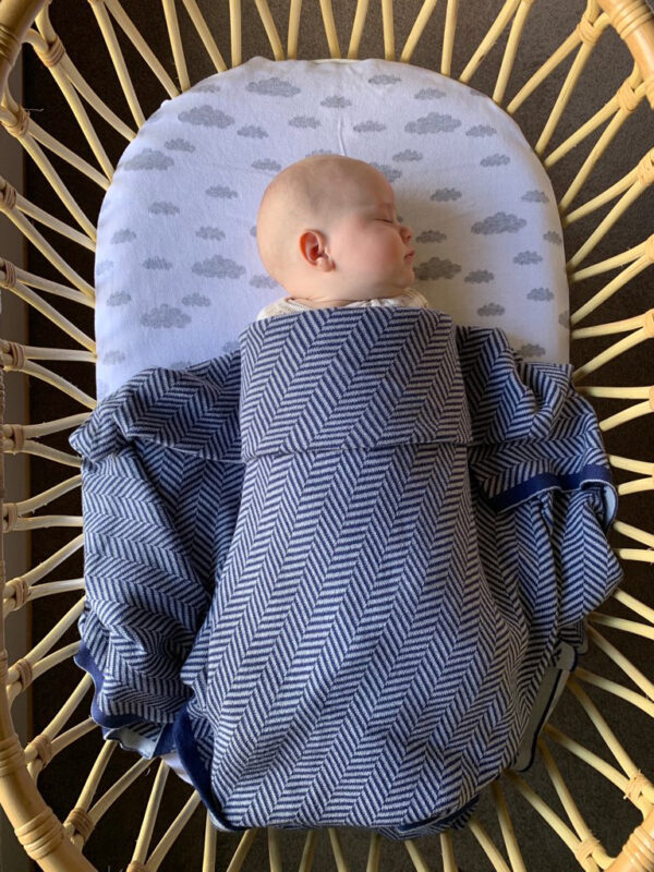 Baby Sleeping in Bassinet under Navy Grey Herringbone Blanket