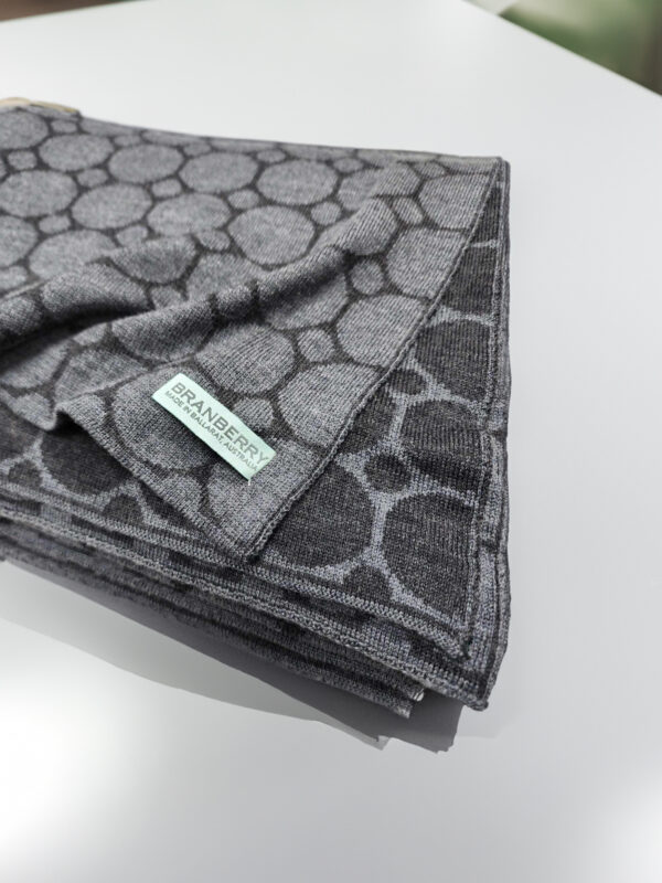 Neatly folded grey Dot to Spot merino wool throw blanket showcasing its soft texture and elegant design